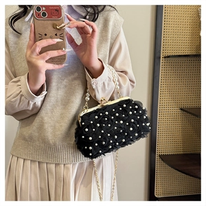 Détail de sac de soirée noir avec fleurs en tulle, perles et bandoulière dorée