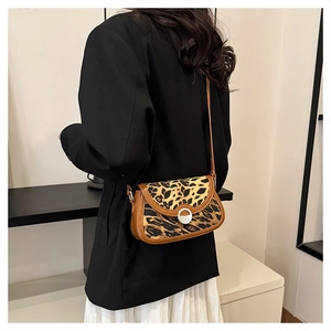 Detail of leopard print crossbody saddle bag showing faux fur texture and leather strap