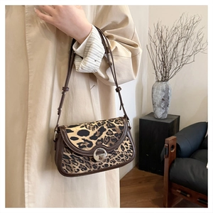 Detail of leopard print crossbody bag with brown leather trim and silver ring lock buckle