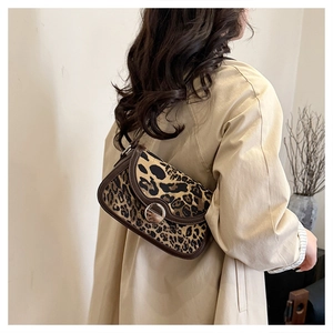 Detailed back view of a leopard print crossbody saddle bag with brown leather trim and metal buckle