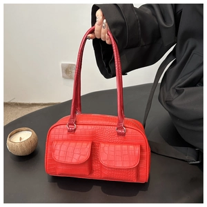 Detail of red crocodile texture handbag featuring two front flap pockets and leather handle
