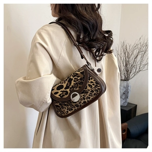 Side view of leopard print underarm bag with silver buckle worn with beige coat