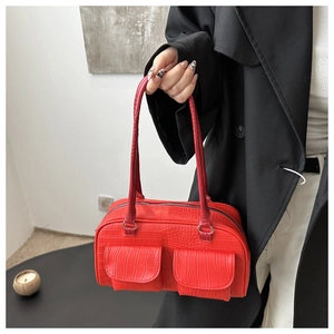 Detail of red crocodile pattern shoulder bag with dual front pockets and glossy texture