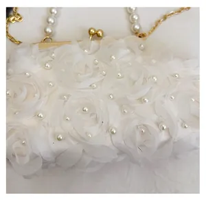 Détail de la pochette de soirée en dentelle blanche avec roses en tissu et perles