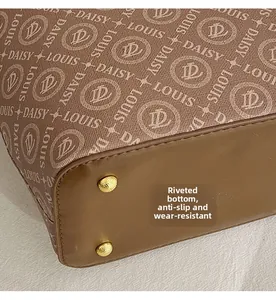 Detail of printed canvas tote bag with gold protective studs and premium leather bottom
