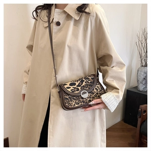 Close-up of leopard print crossbody bag with brown leather trim and metal clasp detail