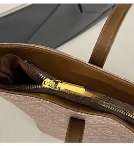 Detail of smooth gold metal zipper and branded jacquard fabric on stylish tote bag