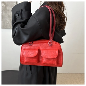 Detail view of red faux crocodile leather shoulder bag featuring dual front flap pockets