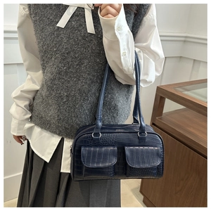 Detail of dark blue faux crocodile texture bag with double flap pockets on mannequin