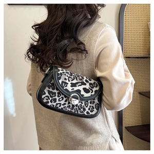 Detail of leopard print saddle bag with silver round buckle shown on a shoulder