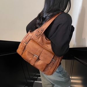 Brown vintage faux leather tote bag with large front pockets shown on shoulder
