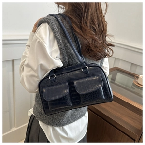 Detail of dark blue crocodile texture leather shoulder bag shown on model's shoulder