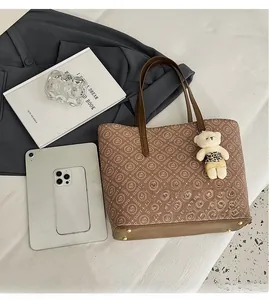 Detail of large tote bag with letter print, golden base rivets and bear charm