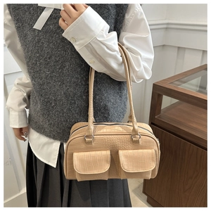 Detail of crocodile textured shoulder bag with dual front pockets and silver hardware