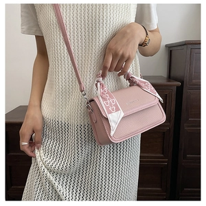Detail of pink lychee leather crossbody bag featuring a silk scarf wrapped handle accent