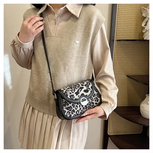 Detail of leopard print crossbody bag with silver buckle worn by a model in casual outfit