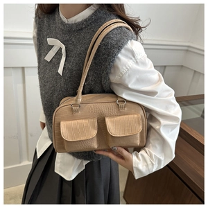 Detail of apricot crocodile texture shoulder bag with dual flap pockets shown on model