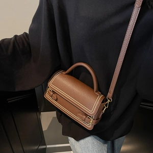 Brown lychee leather crossbody bag with top handle and gold hardware in a front view