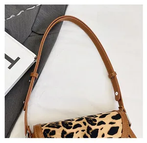 Close-up of leopard print shoulder bag featuring brown leather strap and silver metal buckle