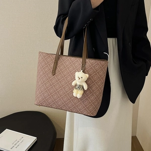 Pink monogram tote bag with brown straps and cute bear charm shown on model