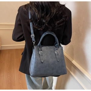Détail du sac Boston gris-bleu avec ferrures argentées sur une tenue décontractée