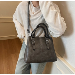Détail du sac cabas en similicuir taupe avec boucles métalliques porté à l'épaule