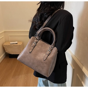 Sac cabas en cuir taupe rétro avec boucles argentées porté par un mannequin chic