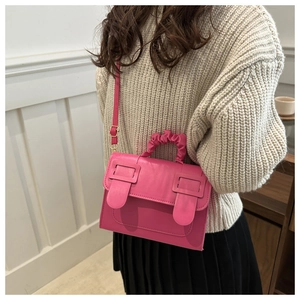 Detailed view of hot pink PU leather crossbody bag with pleated handle and metal buckle