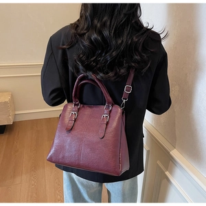 Détail macro du sac à main bordeaux avec grain de litchi et boucles argentées