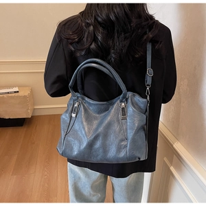 Sac fourre-tout bleu en cuir souple vu de dos dans un intérieur de maison minimaliste