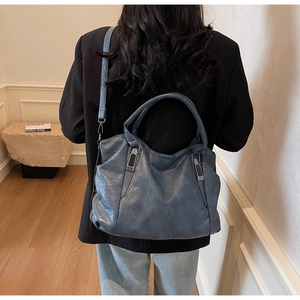 Detail of blue faux leather handbag with metal buckles on a model in a modern interior