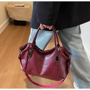 Détail du sac cabas bordeaux en cuir montrant la texture et la bandoulière amovible