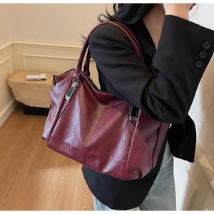 Détail d'un grand sac cabas en cuir souple bordeaux avec des attaches métalliques chic