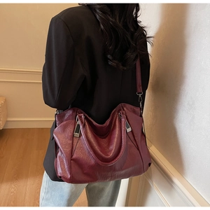 Grand sac cabas en cuir souple bordeaux porté par un mannequin avec boucle en argent