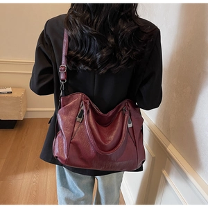 Sac hobo bordeaux avec texture litchi et détails argentés porté par un mannequin