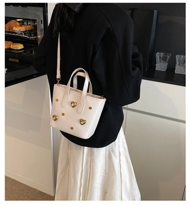 Detailed view of a white tote bag featuring heart-shaped rhinestones and adjustable strap