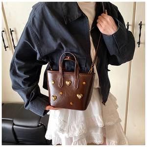 Detail of dark brown vintage tote bag with heart-shaped crystals and metallic studs