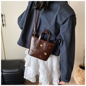 Detail of dark brown bucket bag with gold heart studs and sparkling rhinestone accents