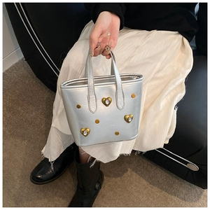Close-up of silver leather tote featuring golden heart buckles and sparkling crystals