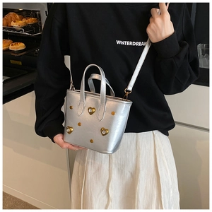 Silver leather bucket bag with rhinestone studs shown on shoulder for sizing