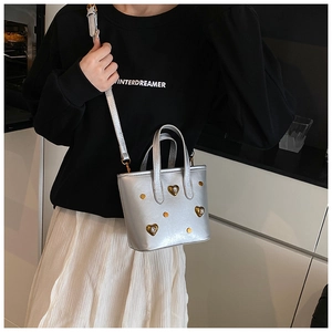 Detail of silver metallic bucket bag featuring heart-shaped rhinestones and studs