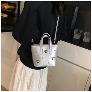 Detail of silver bucket bag with glittering heart rivets and crossbody strap