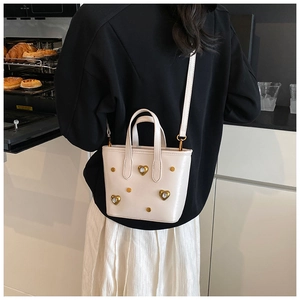 Close-up of beige bucket bag with gold rhinestone hearts shown in a kitchen setting
