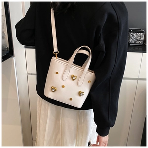 Detailed view of white bucket bag with golden heart rhinestones and rivet accents