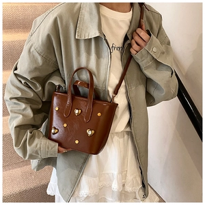 Detail of brown leather bucket bag featuring gold heart rhinestones and rivets decorations