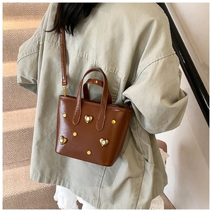 Deep brown bucket bag with crystal hearts and studs shown on a model in a lifestyle setting