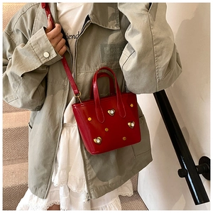 Detail of red patent leather bucket bag with gold heart rhinestones and studs