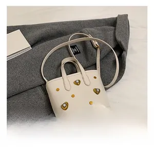 Detail of cream white bucket bag featuring golden heart buckle and studded accents