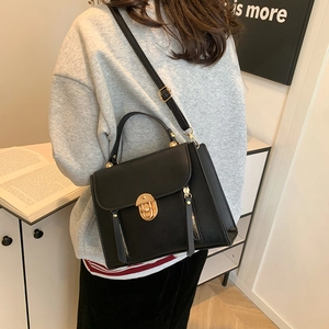 Classic black leather messenger bag with gold circular lock shown in a home setting