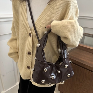 Sac nuage en cuir marron avec rivets et bandoulière porté par un mannequin